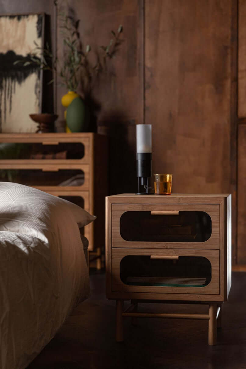 Table de nuit en bois avec verres, 2 tiroirs, ambiance chaleureuse et élégante, décoration intérieure.